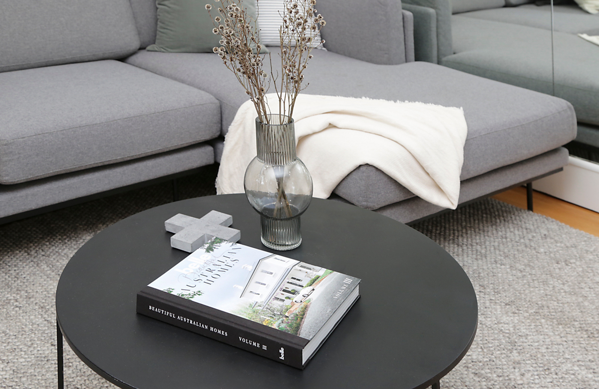 Living room with grey lounge and black coffee table styled with Belle Beautiful Australian Homes book