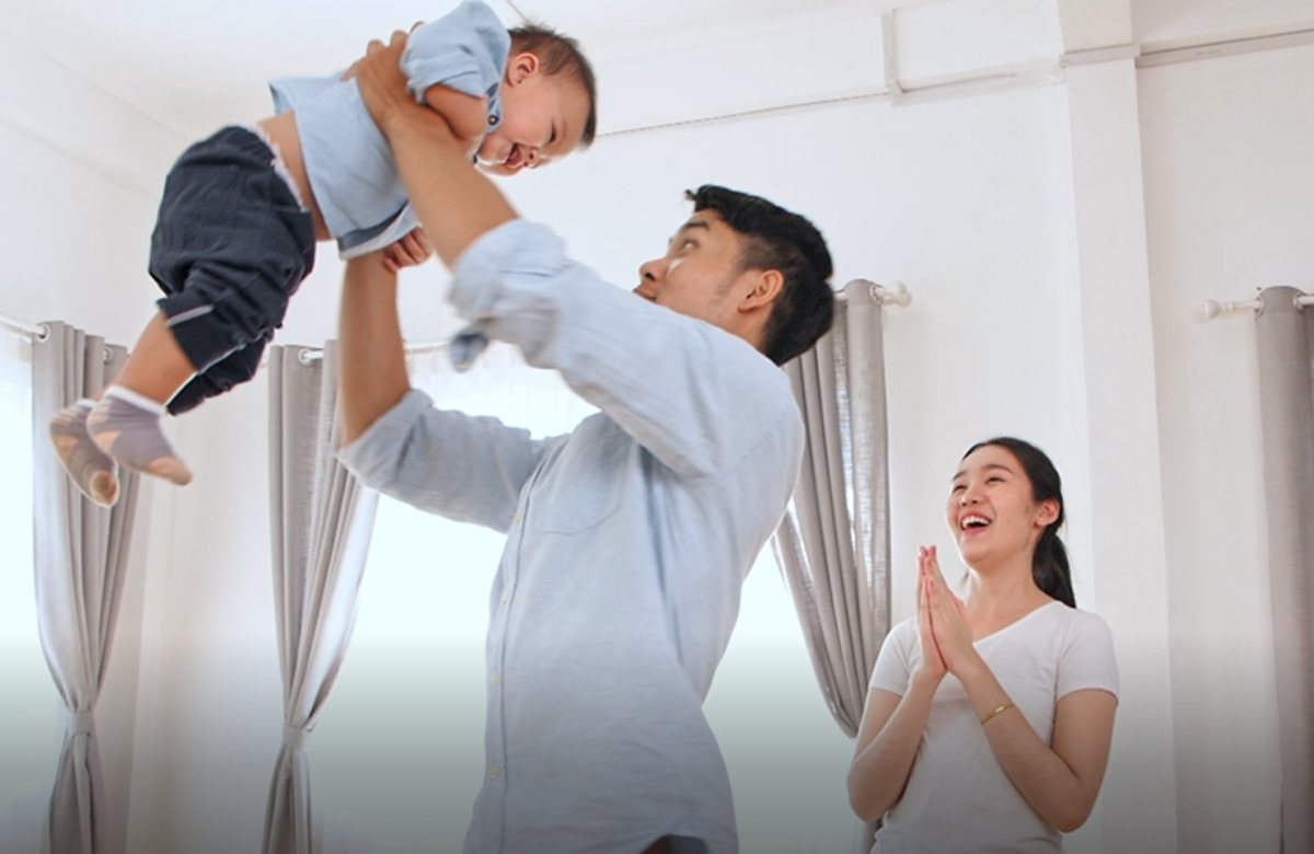 Young family in home, man holding baby up in the air
